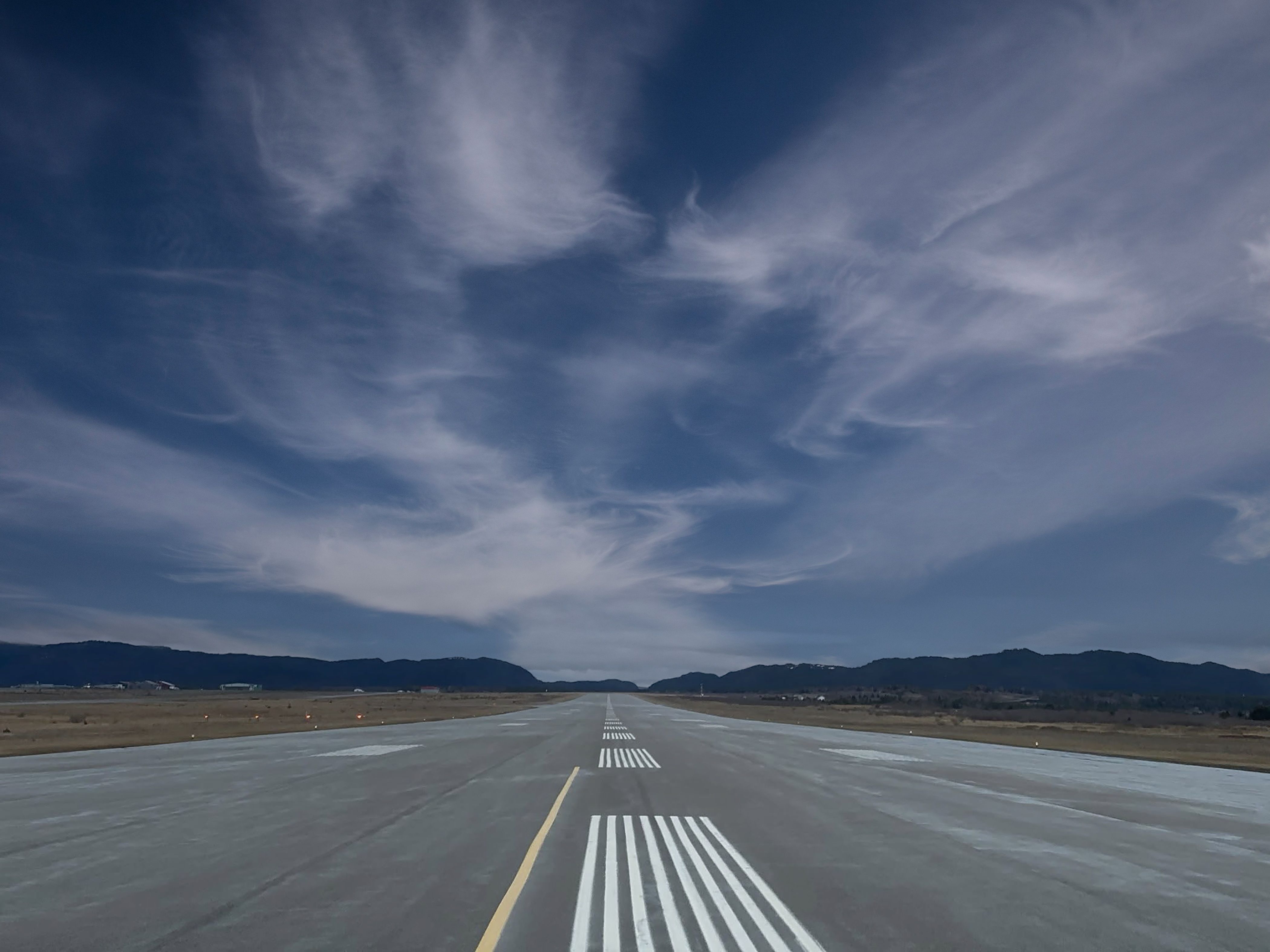 Looking down the full length of the Stephenville runway under a blue sky, mountains at the far end.